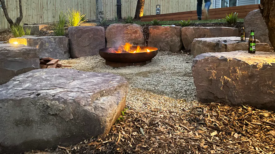 Family home in Montmorency, Melbourne with full front and backyard landscaping by Land Sculpture shown at dusk with garden lighting and fire pit