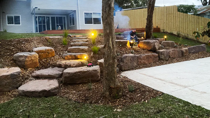 Family home in Montmorency, Melbourne with full front and backyard landscaping by Land Sculpture shown at dusk with garden lighting