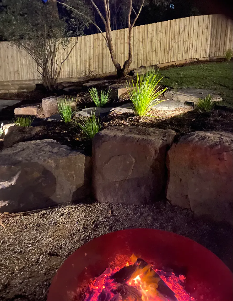 Landscaped backyard in Montmorency, Melbourne at night with fire pit