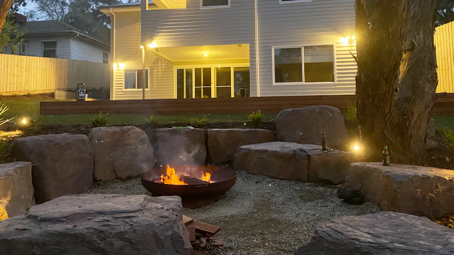 Family home in Montmorency, Melbourne with full front and backyard landscaping by Land Sculpture shown at night with garden lighting and fire pit