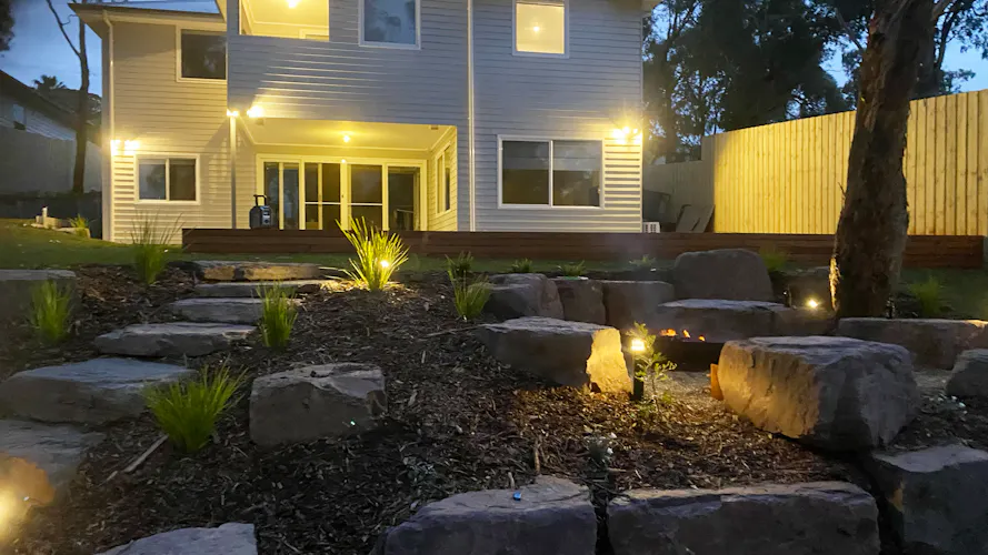 Family home in Montmorency, Melbourne with full front and backyard landscaping by Land Sculpture shown at night with garden lighting
